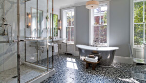 Spacious modern bathroom featuring a freestanding tub, glass shower, and intricate floor tiles.